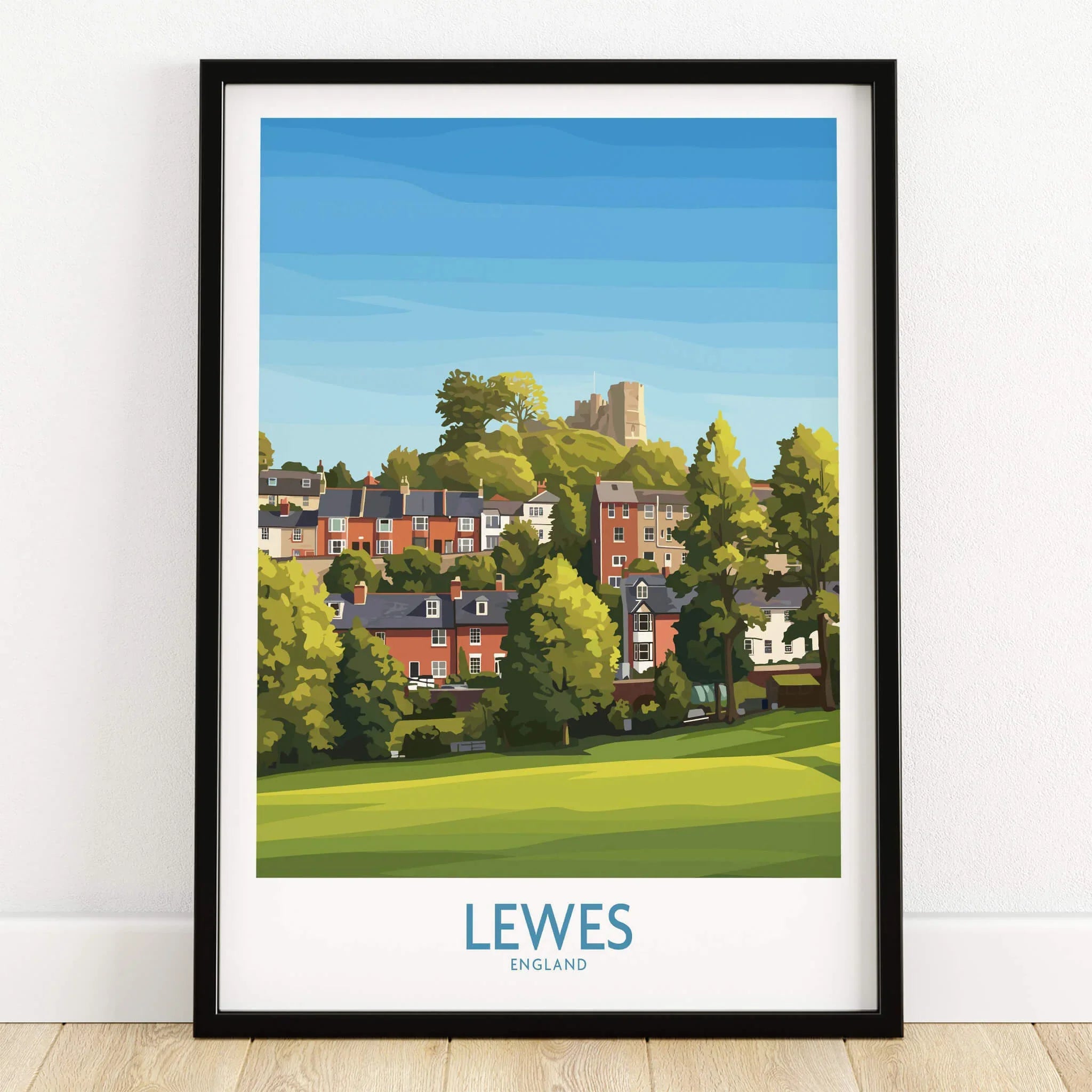 Lewes England art print in black frame, featuring colorful houses, greenery, and a castle.
