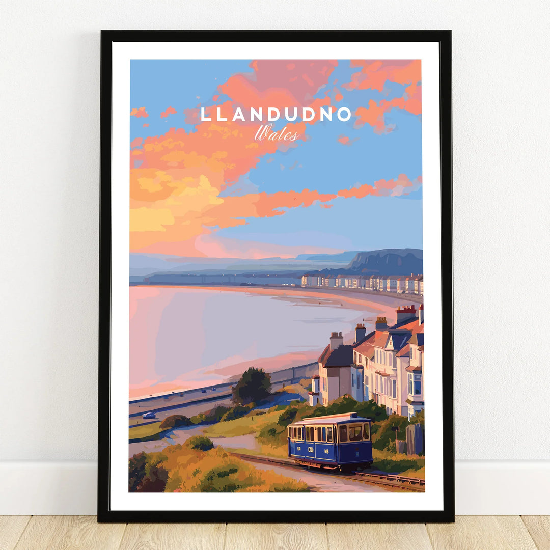 Llandudno Wales travel poster art print with tram, coastal houses, and sunset in black frame.