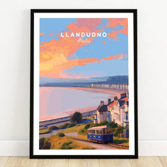 Llandudno Wales travel poster art print with tram, coastal houses, and sunset in black frame.