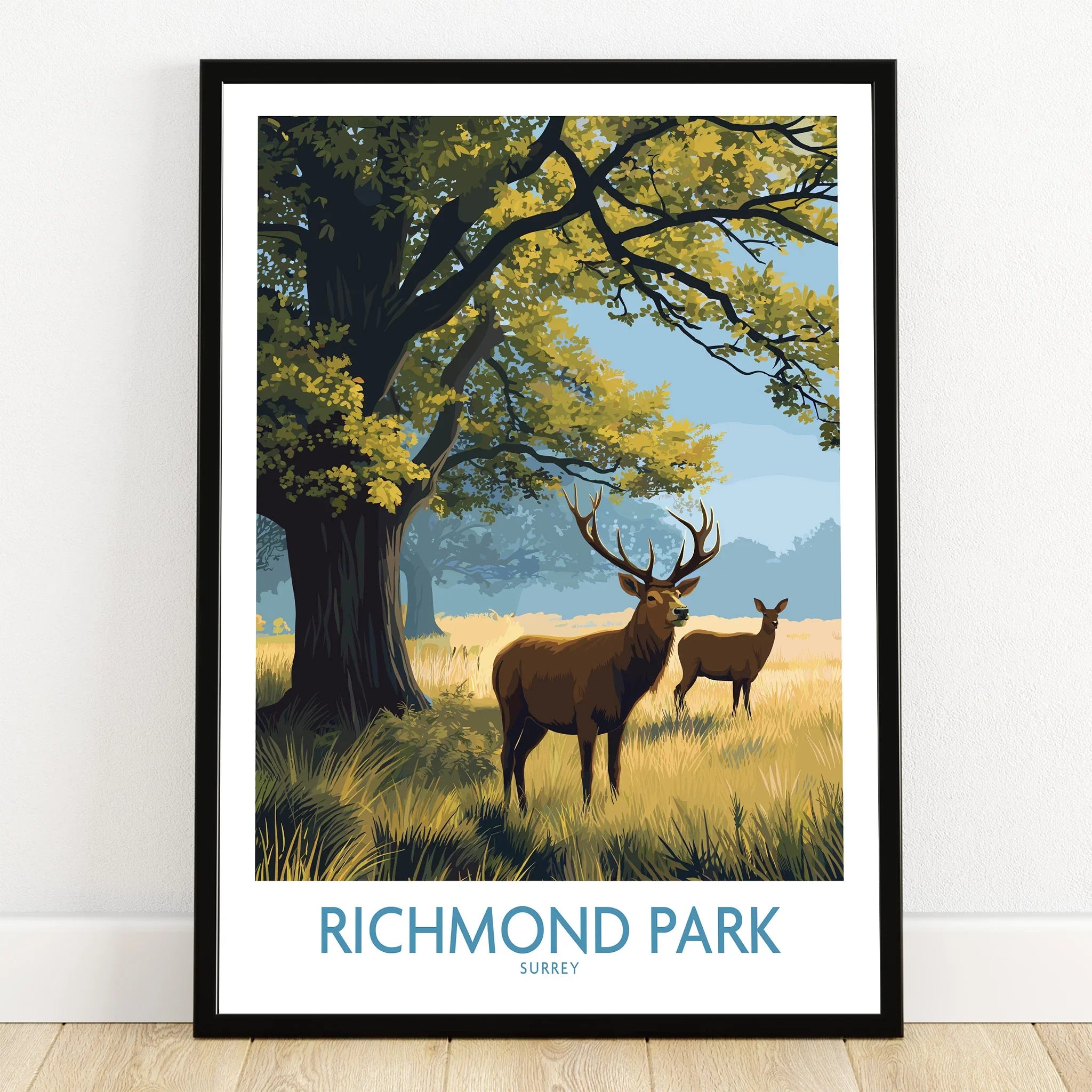 Richmond Park travel poster print with deer and trees in black frame on wooden floor