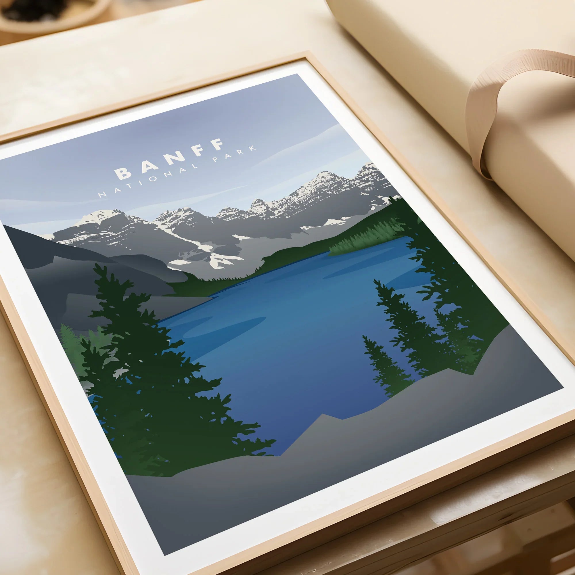 Framed Banff National Park art print with mountains, lake, and pine trees in a natural wood frame.