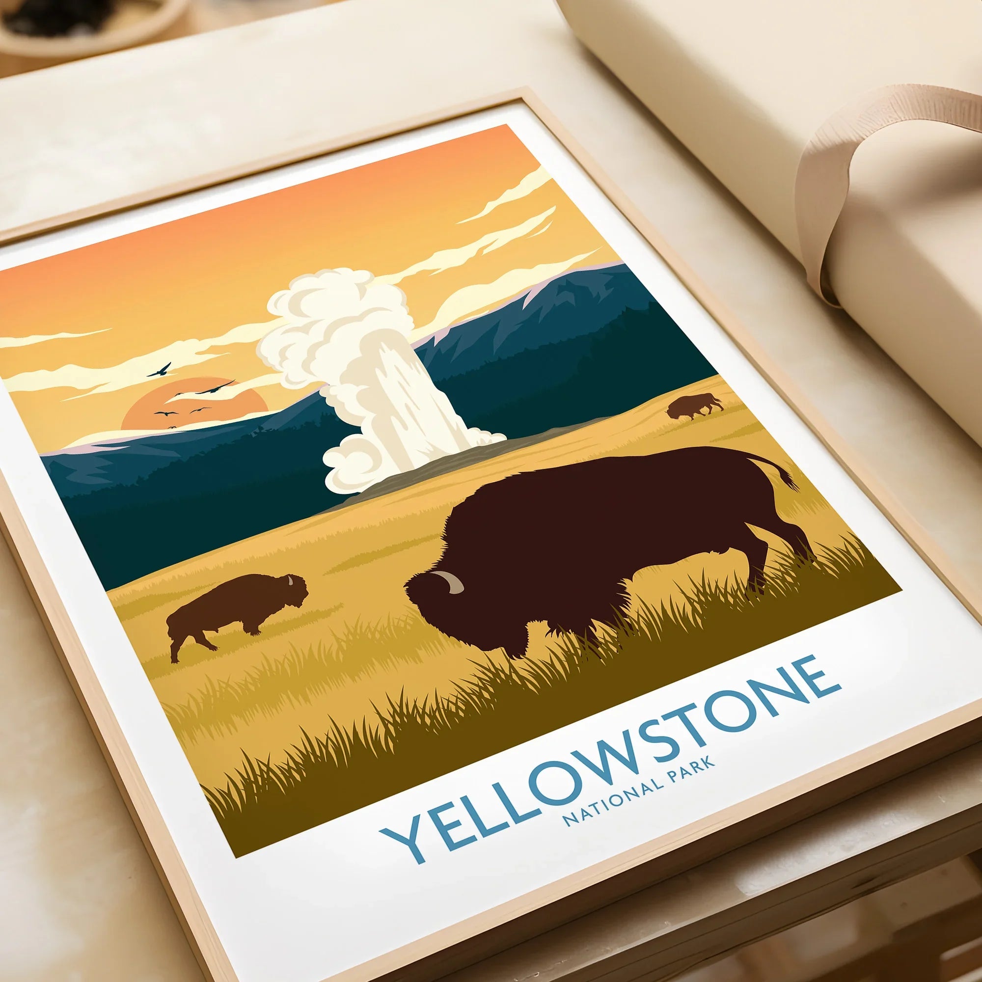 Framed Yellowstone National Park art print featuring bison, mountains, and a geyser at sunset