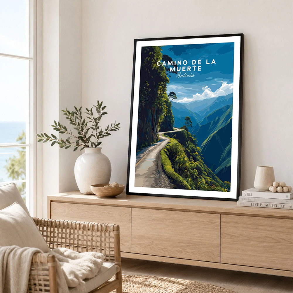 Camino de la Muerte Poster Bolivia Wall Art in a black frame displayed on an oak sideboard in a bright coastal living room