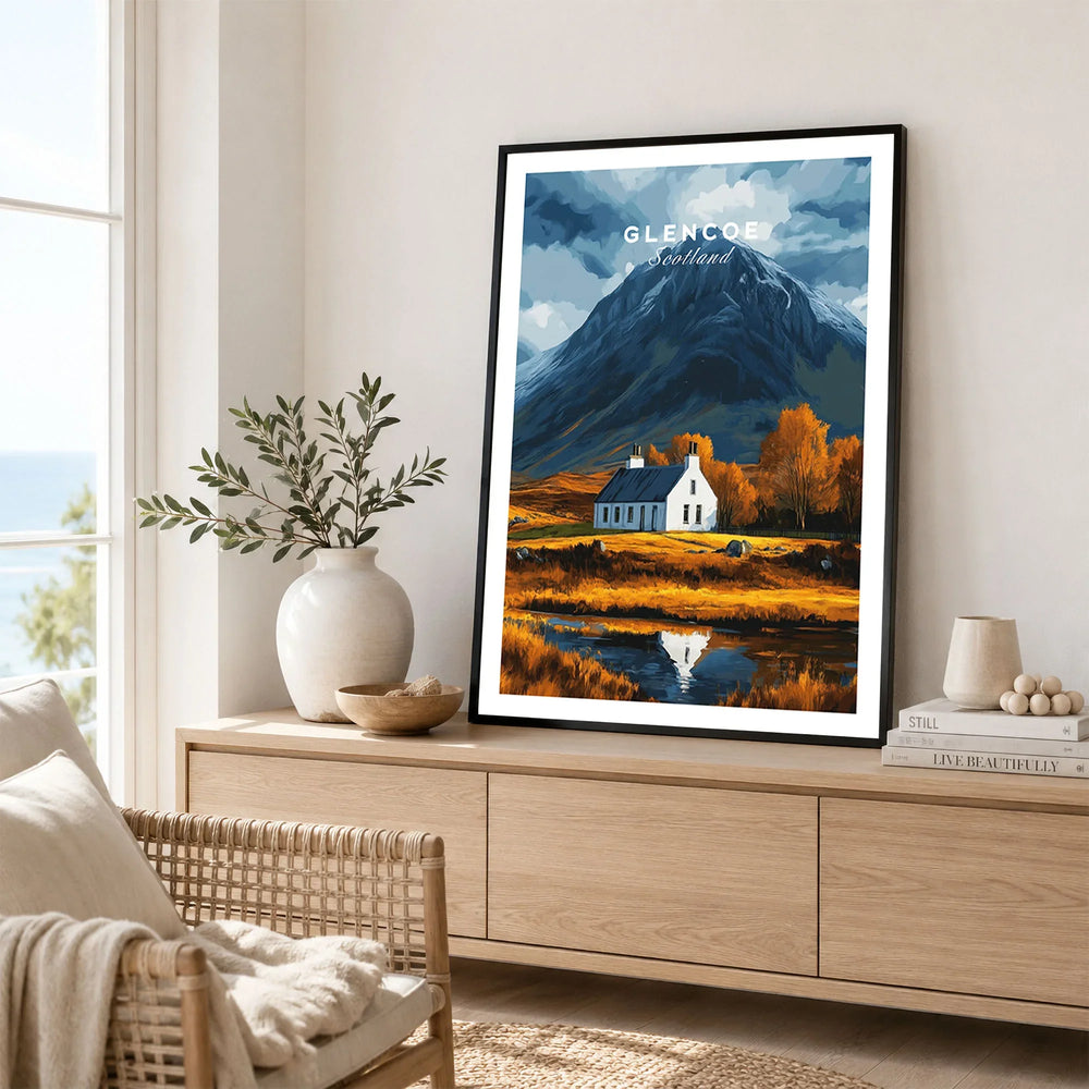 Glencoe Scotland Poster in a black frame displayed on an oak sideboard in a bright coastal living room