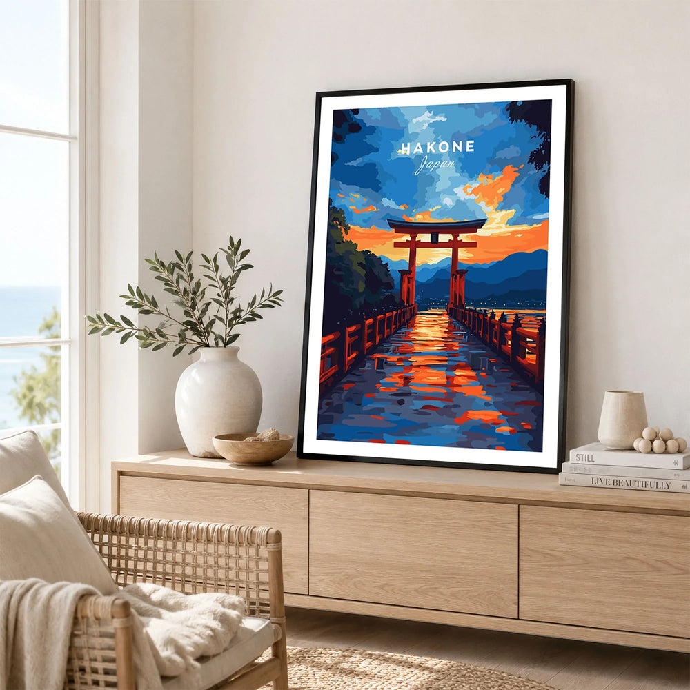 Hakone Wall Art Japan Torii Gate Sunset Reflections Poster - Vibrant Lake Ashi Print in a black frame displayed on an oak sideboard in a bright coastal living room