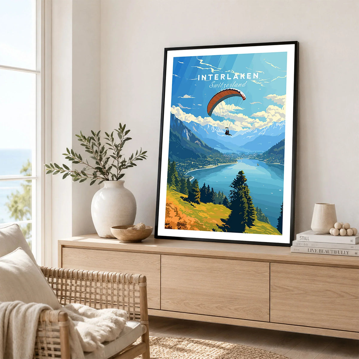 Interlaken Switzerland Poster in a black frame displayed on an oak sideboard in a bright coastal living room