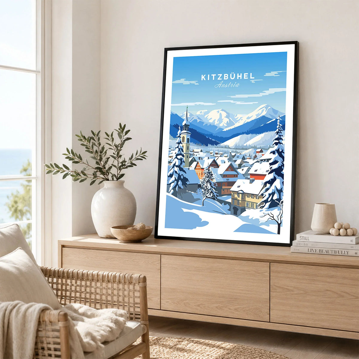 Kitzbuhel Poster in a black frame displayed on an oak sideboard in a bright coastal living room