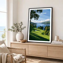 Loch Lomond Scotland Summer Shore Travel Poster — a sunlit grassy shoreline running down to Loch Lomond under old oaks, shown as framed artwork living room lifestyle setting