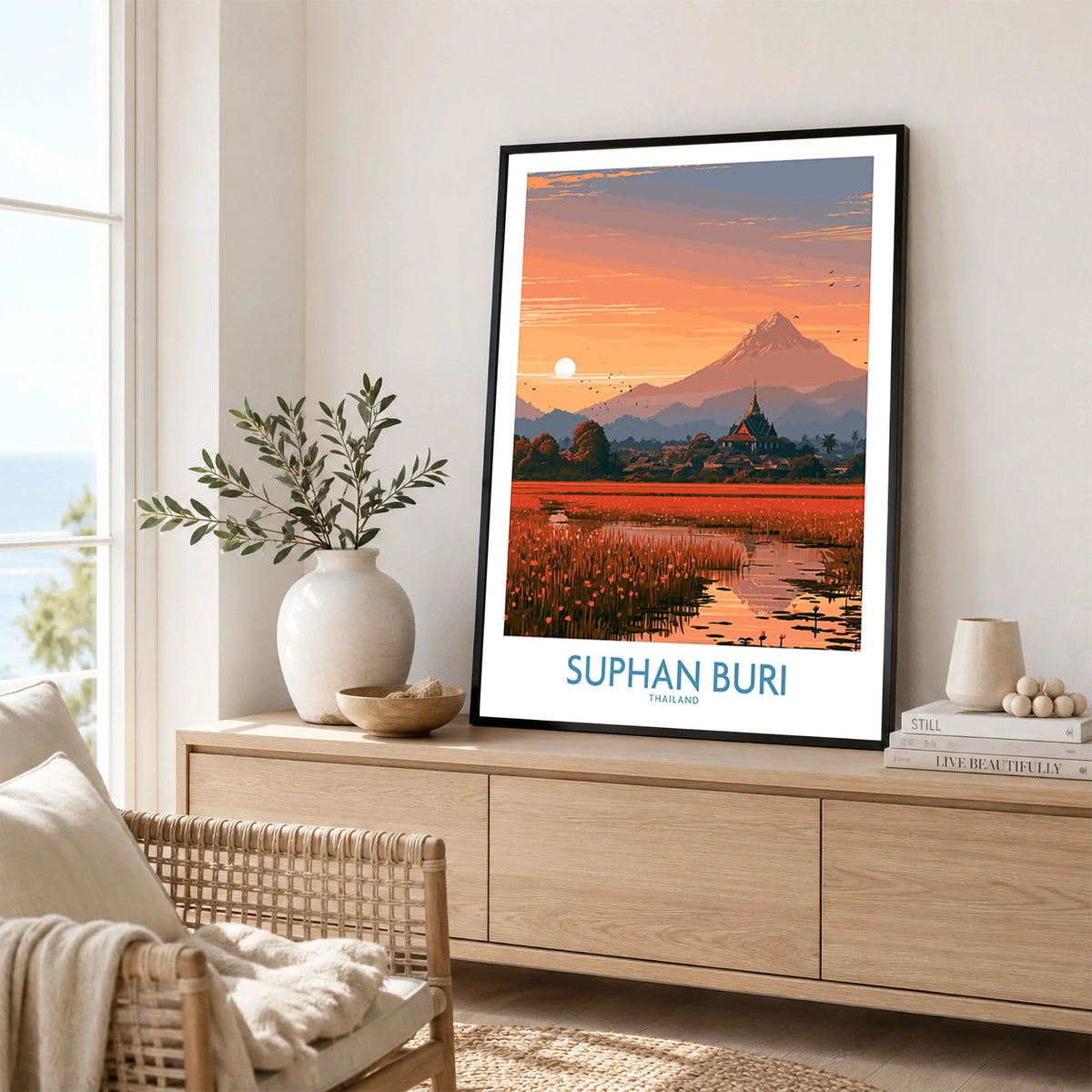 Suphan Buri Thailand Temple Sunset Wall Art — a lotus-covered lake and temple spire at sunset beneath a mountain peak, shown as framed artwork living room lifestyle setting