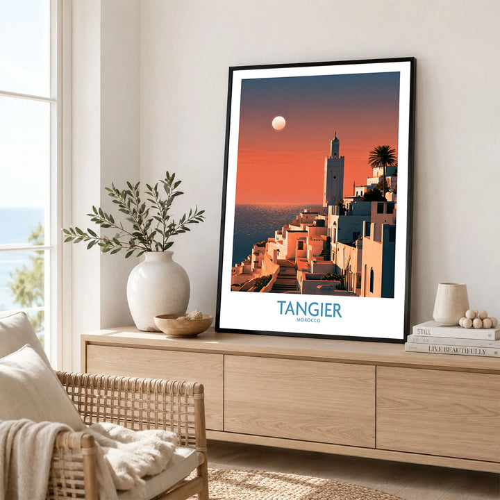 Tangier Morocco Coastal Sunset Wall Art — a whitewashed hillside town and minaret glowing above the sea at sunset, shown as framed artwork living room lifestyle setting