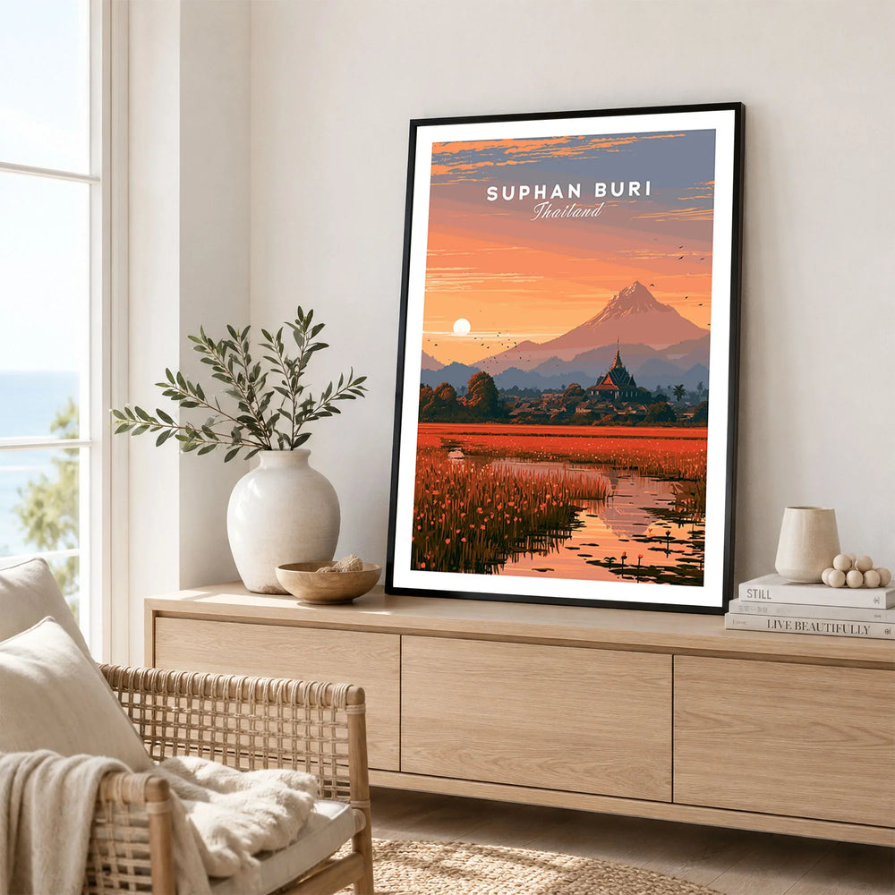 Suphan Buri Thailand Lotus Lake Travel Poster — a lotus-covered lake and temple spire at sunset beneath a mountain peak, shown as framed artwork living room lifestyle setting