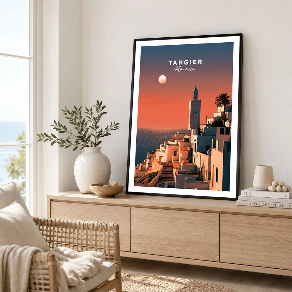 Tangier Morocco Golden Hour Travel Poster — a whitewashed hillside town and minaret glowing above the sea at sunset, shown as framed artwork living room lifestyle setting