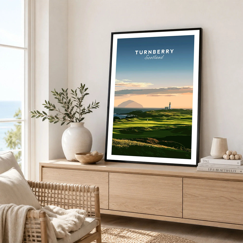 Turnberry Scotland Ailsa Craig Travel Poster — Ailsa Craig and the white lighthouse across rolling coastal turf at dusk, shown as framed artwork living room lifestyle setting