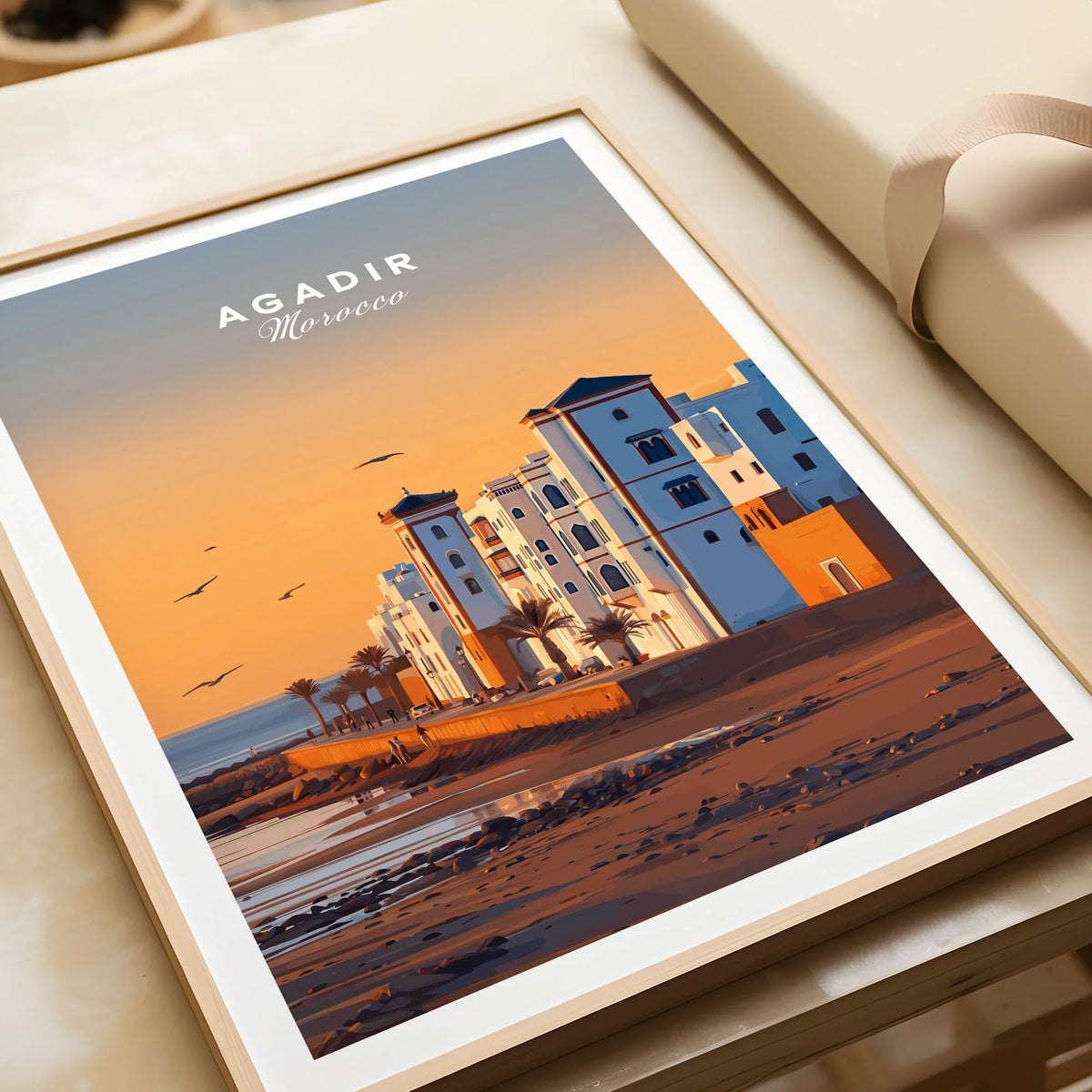 Agadir Travel Poster – Morocco Beach Print in a natural wood frame beside wrapped gift packaging, close-up detail