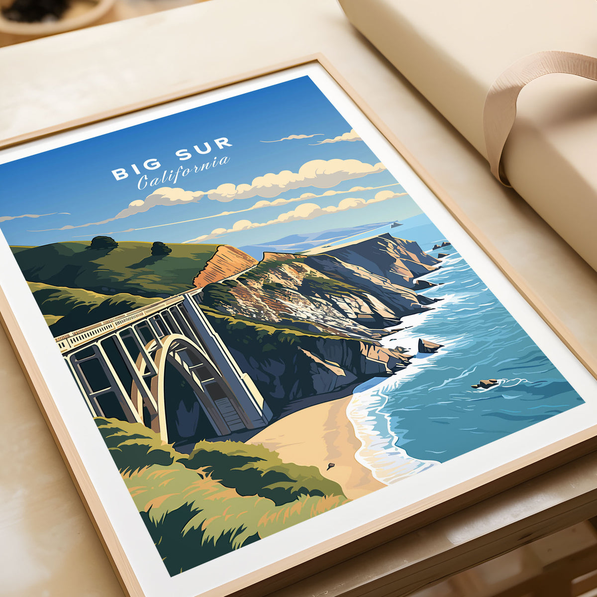 Big Sur Print in a natural wood frame beside wrapped gift packaging, close-up detail