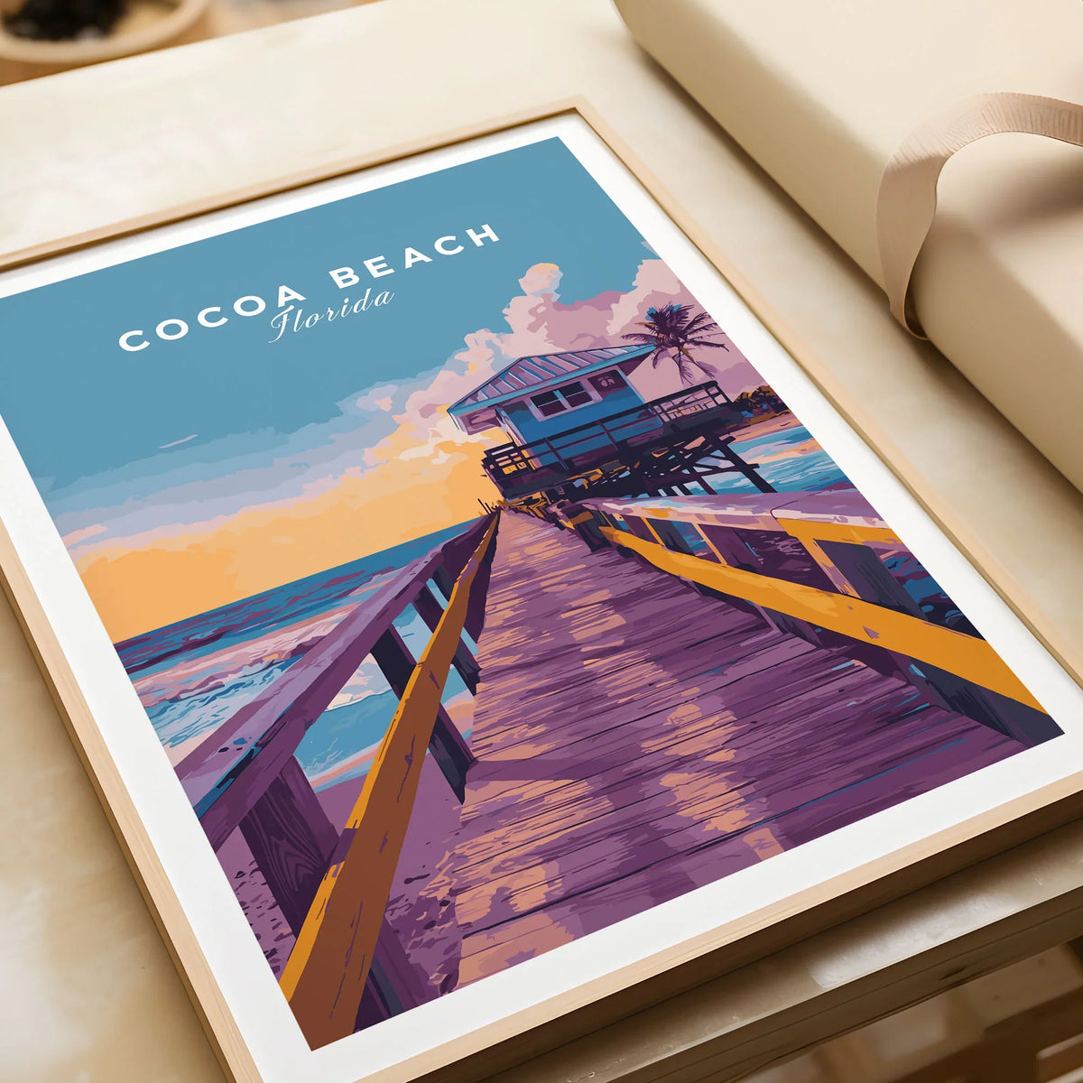 Cocoa Beach Boardwalk Print - Florida Sunset Wall Art in a natural wood frame beside wrapped gift packaging, close-up detail