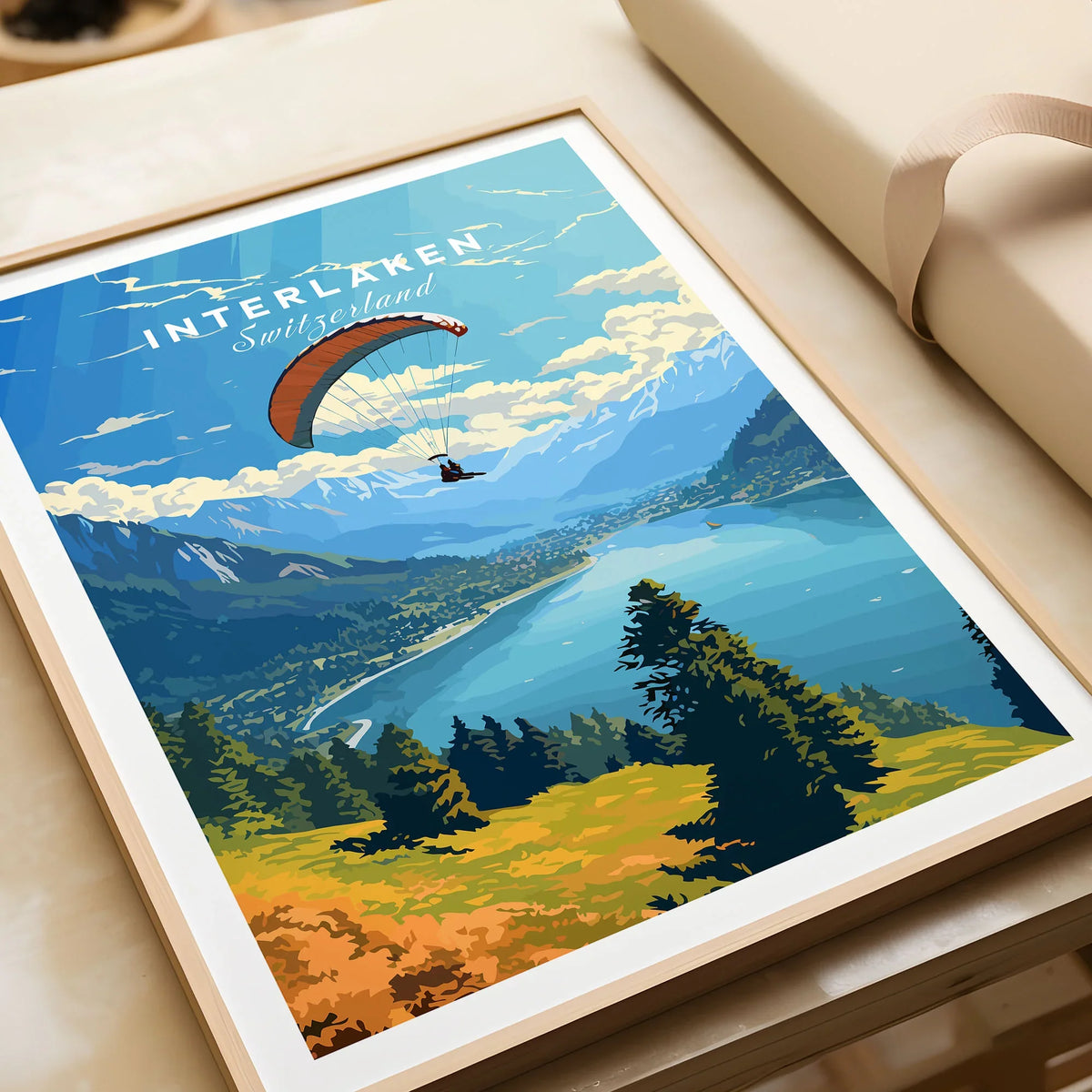 Interlaken Switzerland Poster in a natural wood frame beside wrapped gift packaging, close-up detail