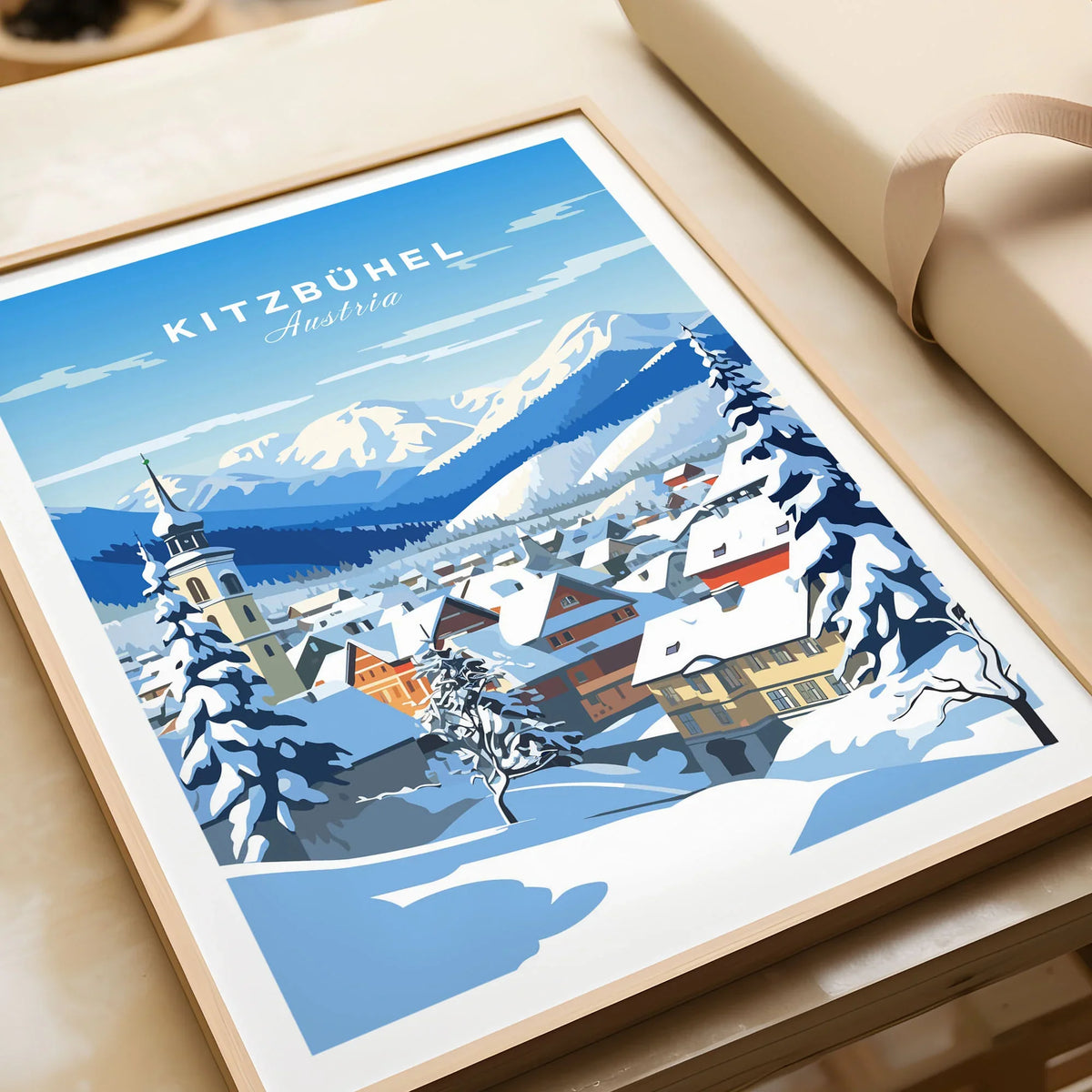 Kitzbuhel Poster in a natural wood frame beside wrapped gift packaging, close-up detail