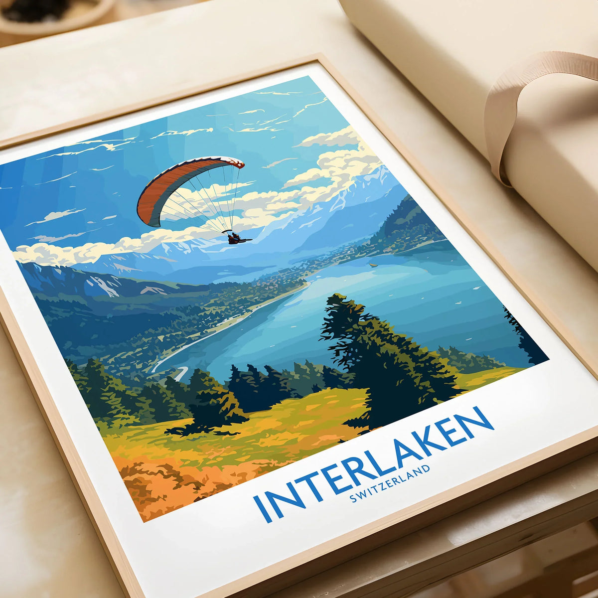 Interlaken Wall Art Print in a natural wood frame beside wrapped gift packaging, close-up detail
