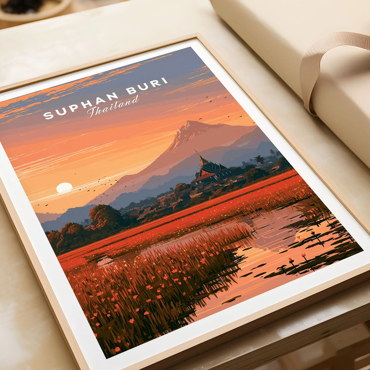 Suphan Buri Thailand Lotus Lake Travel Poster — a lotus-covered lake and temple spire at sunset beneath a mountain peak, shown as framed art print closeup gift unwrapped natural frame