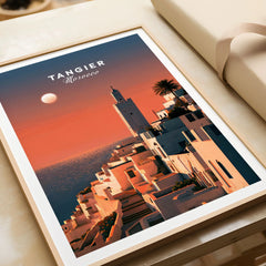 Tangier Morocco Golden Hour Travel Poster — a whitewashed hillside town and minaret glowing above the sea at sunset, shown as framed art print closeup gift unwrapped natural frame
