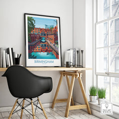 Framed Birmingham city travel poster on modern office desk, black chair, bright window.