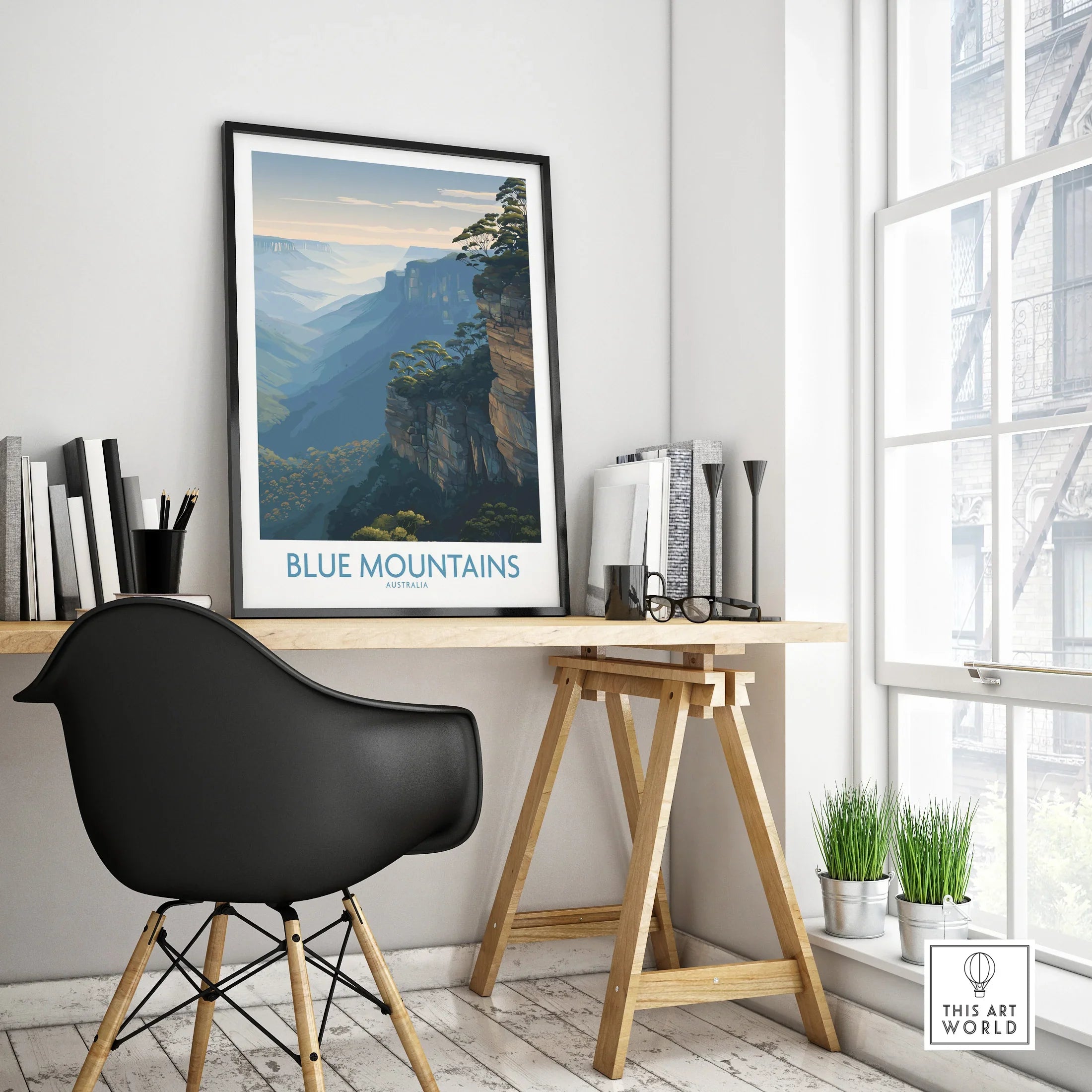 Framed Blue Mountains travel poster on modern office desk with black chair and plants.