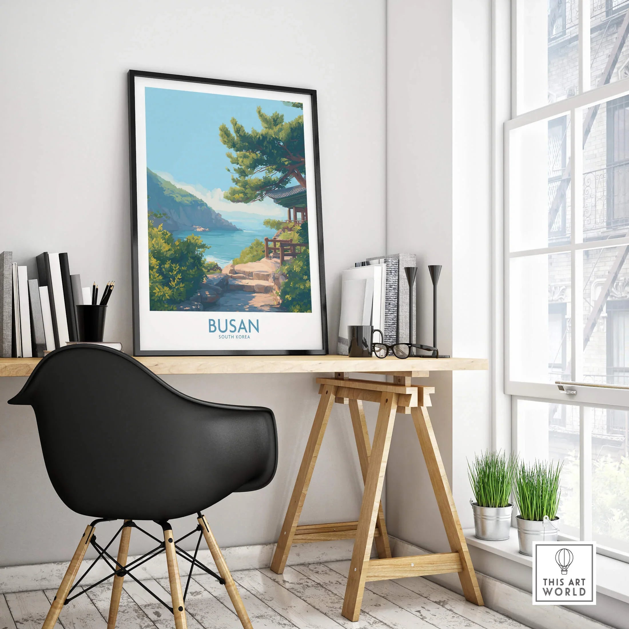 Framed Busan travel poster with scenic coastal art on a modern home office desk