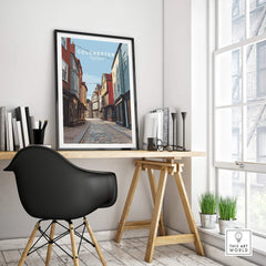 Framed Colchester England travel poster on a modern office desk with cityscape art decor.