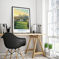 Framed Greenwich London travel poster on modern office desk beside black chair and indoor plants
