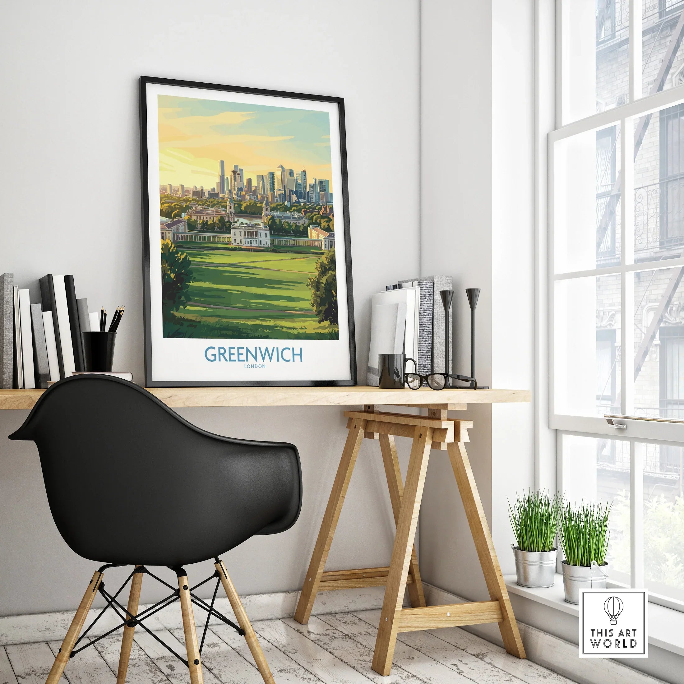 Framed Greenwich London travel poster on modern office desk beside black chair and indoor plants