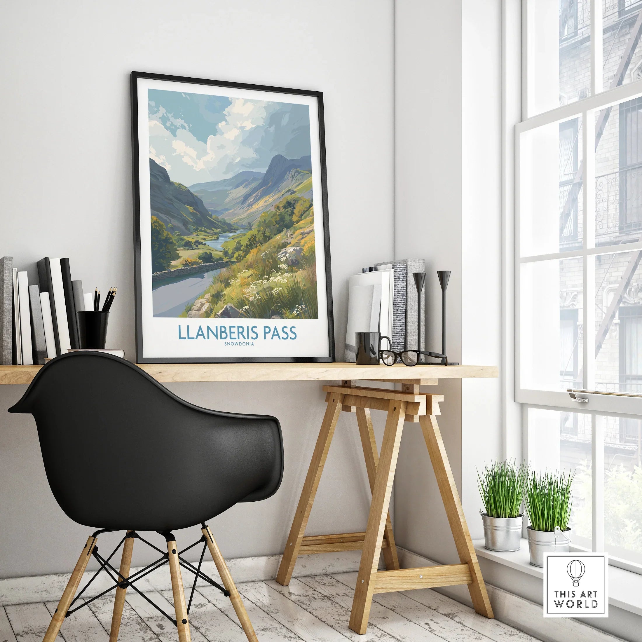 Framed Llanberis Pass travel poster on modern office desk with black chair and window view.