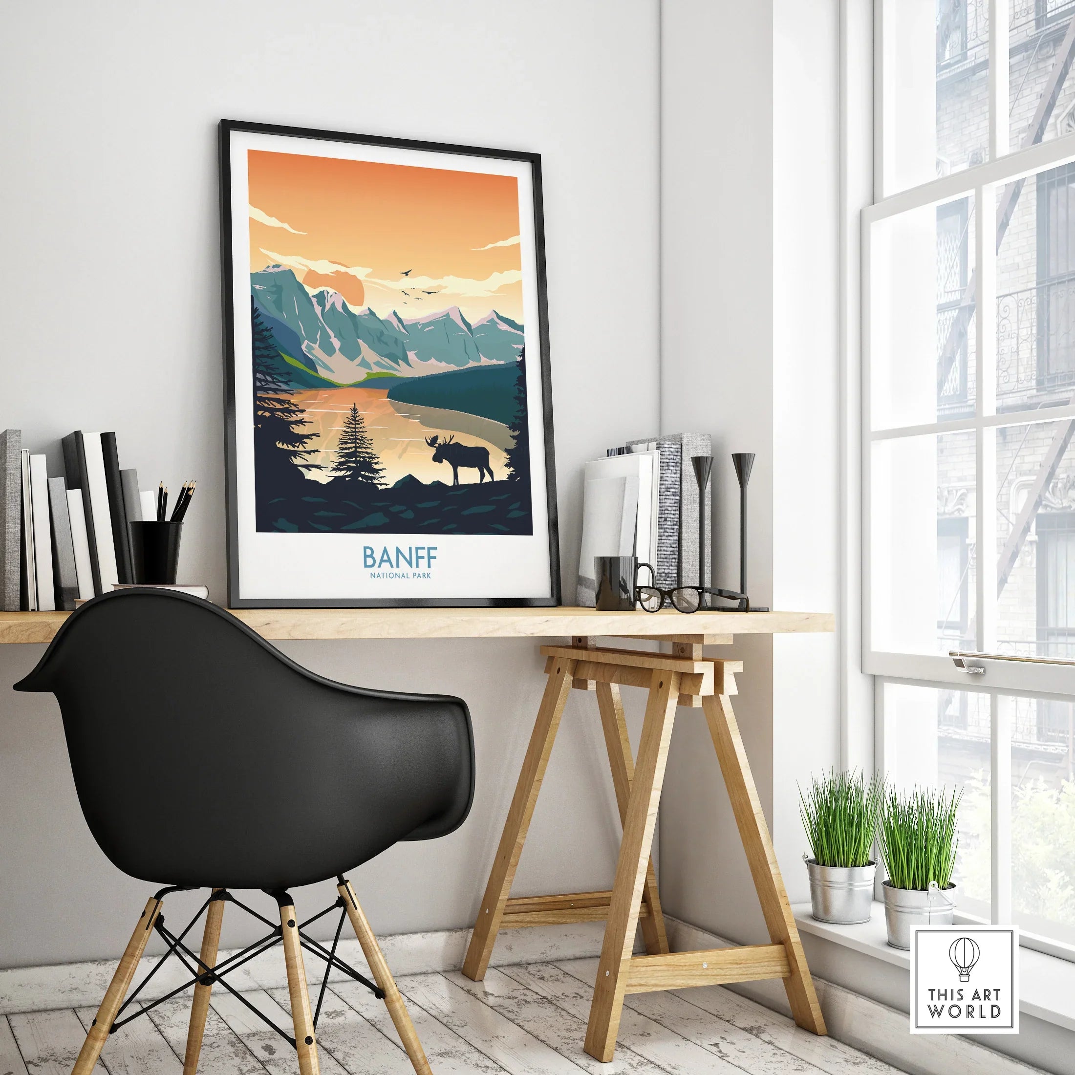 Framed Banff National Park travel poster on modern office desk, black chair, natural decor