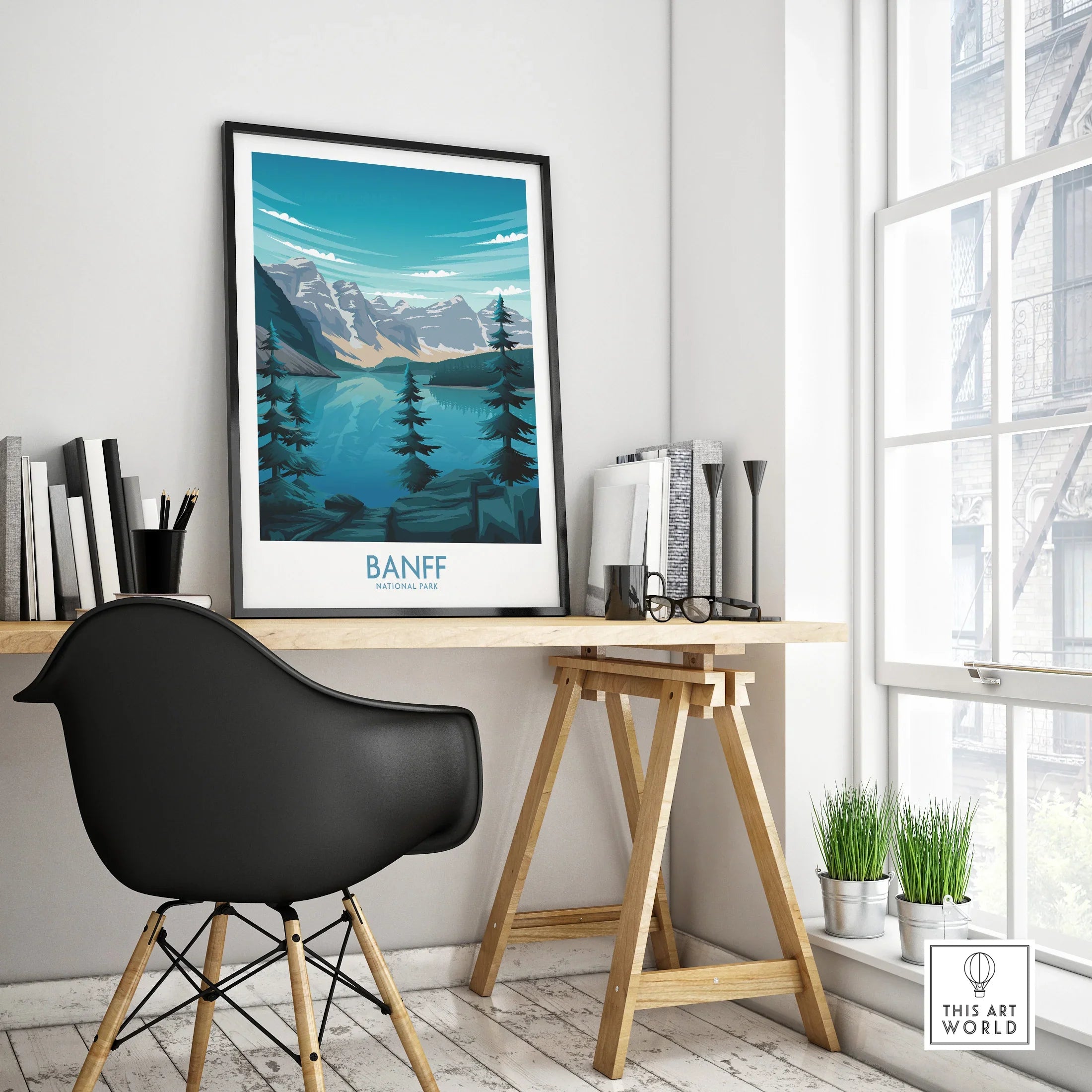 Banff National Park travel poster with mountains, lake, and pine trees in a black frame on a modern office desk