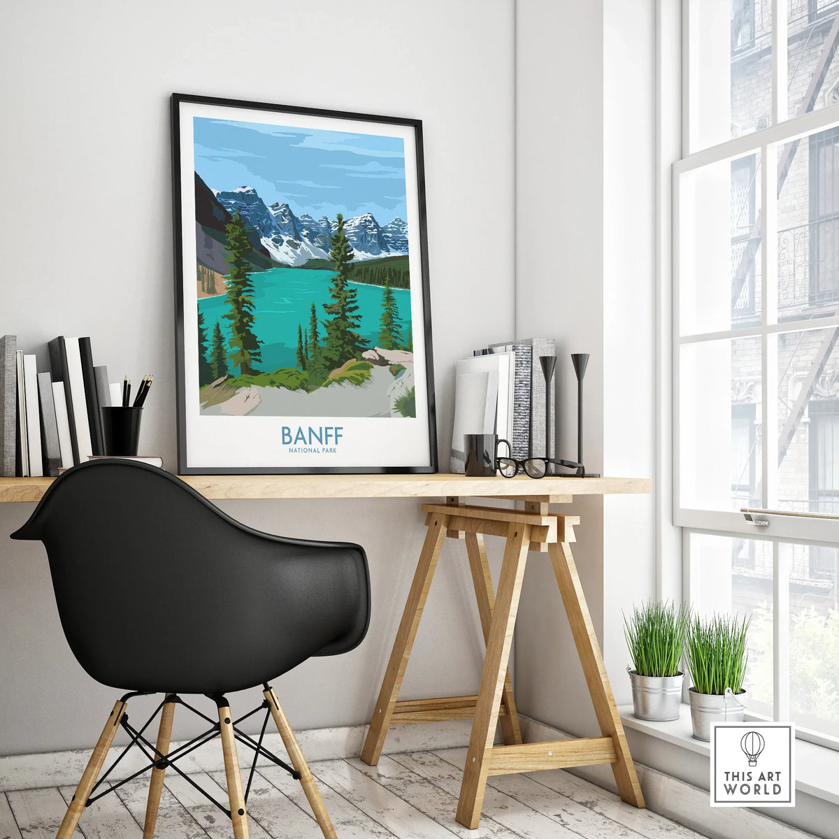 Banff National Park travel poster in black frame on a modern office desk, natural light
