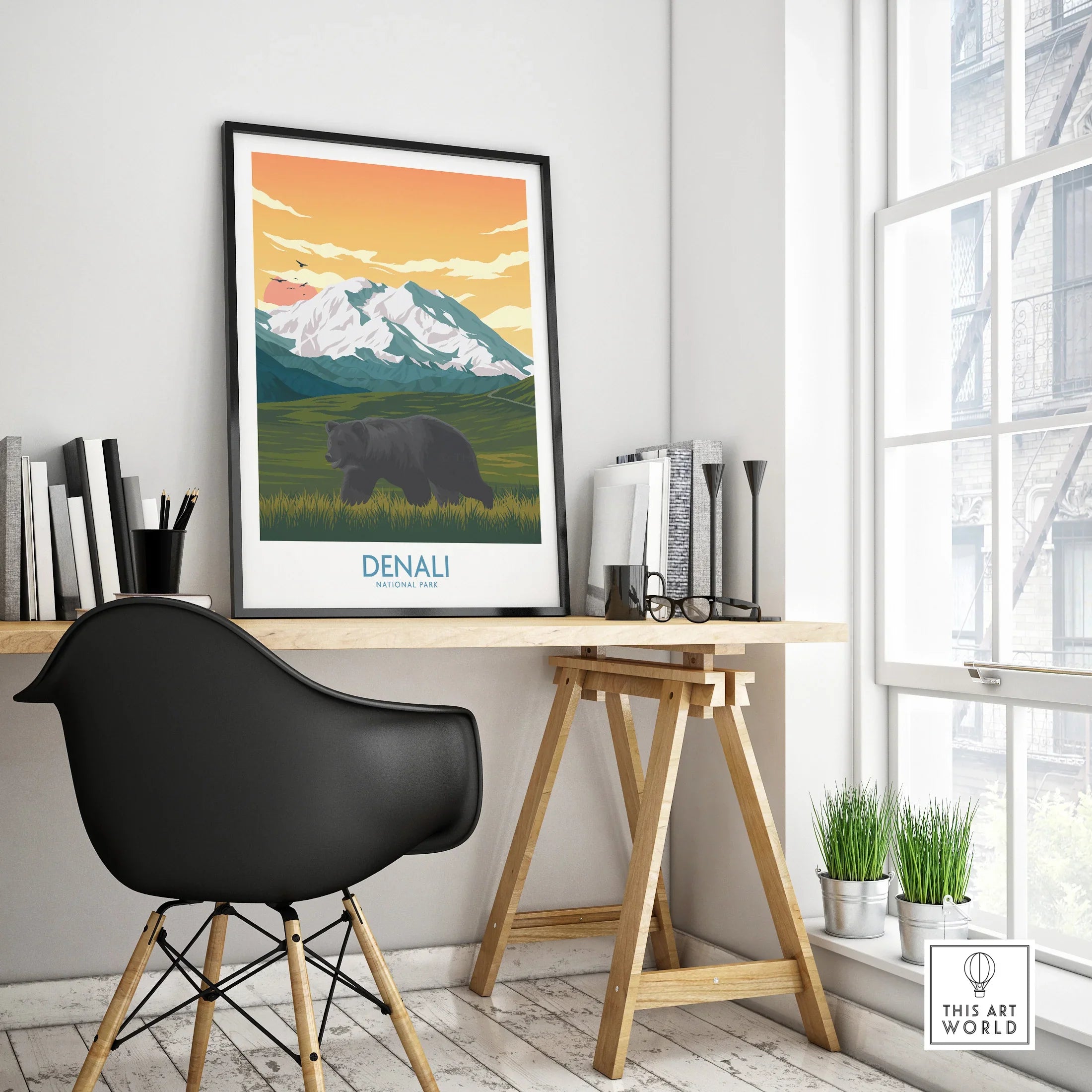 Framed Denali National Park travel poster on modern office desk with mountain and bear illustration
