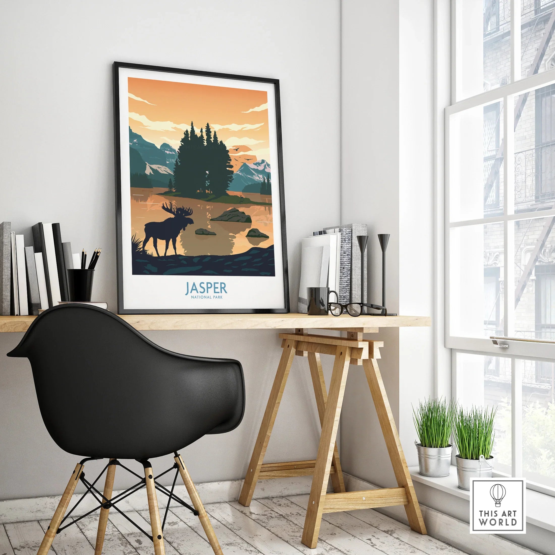 Jasper National Park travel poster with moose and mountains in black frame on modern office desk.