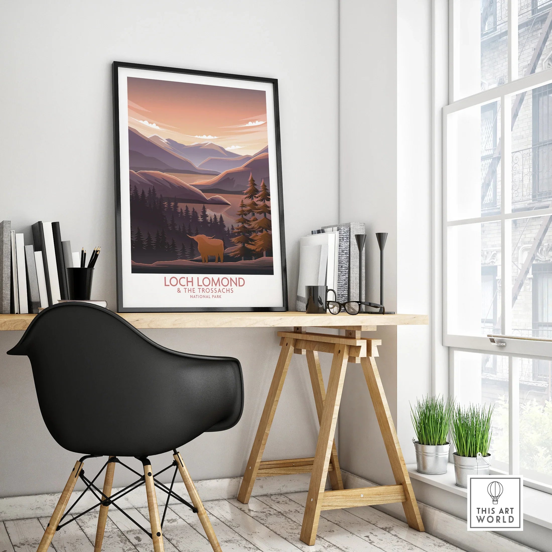 Framed Loch Lomond National Park art poster on a modern office desk in a bright room.