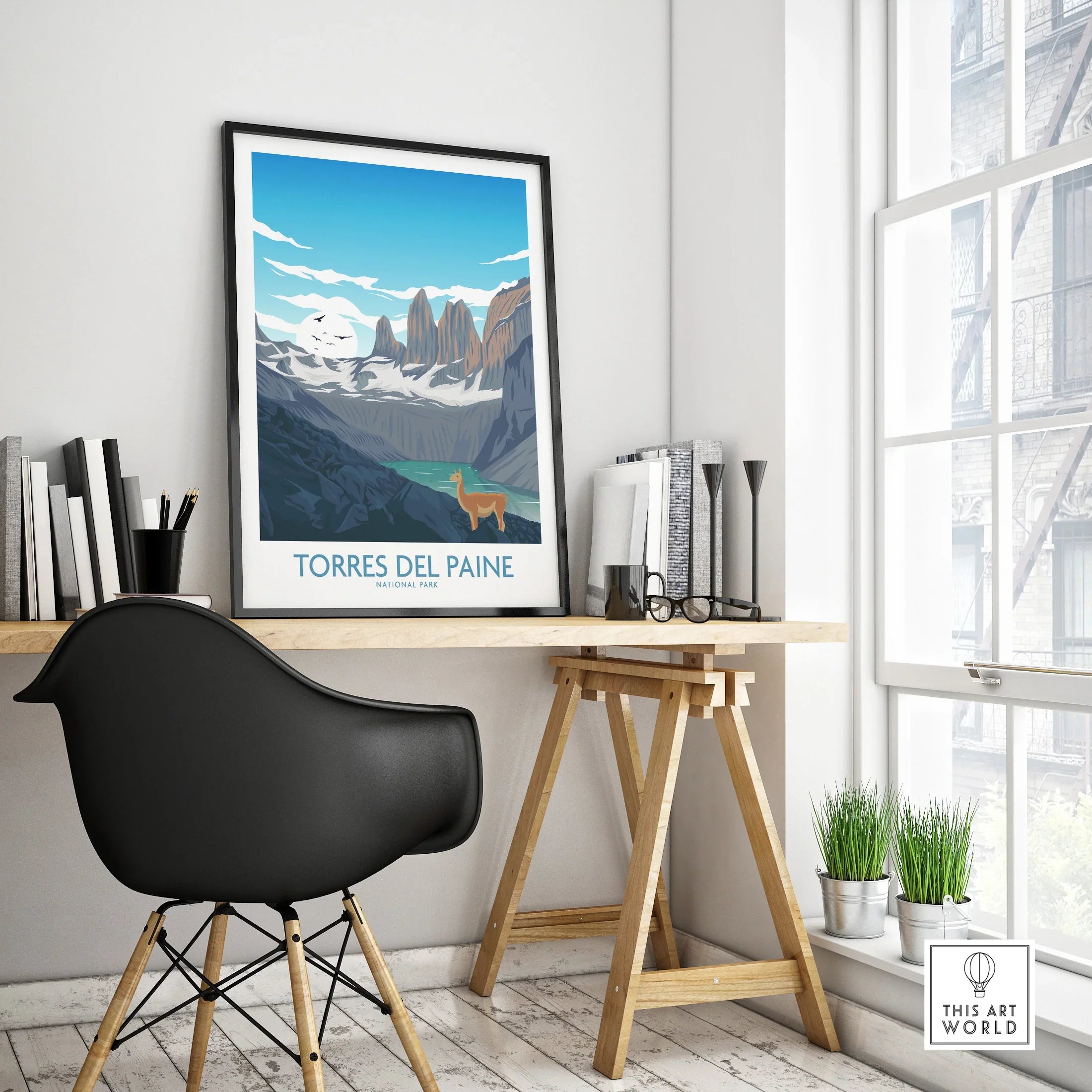 Framed Torres del Paine National Park poster on a modern office desk by window