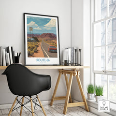Framed Route 66 travel poster on modern office desk, mid-century red car, mountain landscape art