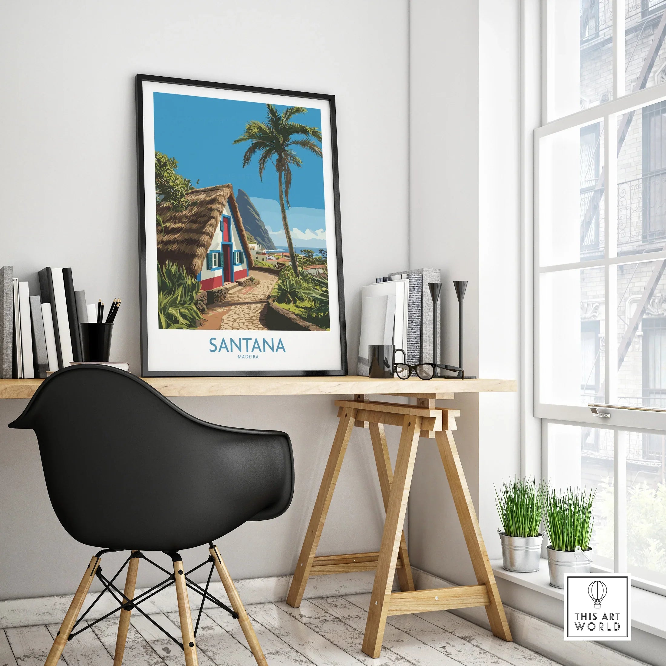 Framed Santana Madeira travel poster on modern office desk by window, black chair nearby.