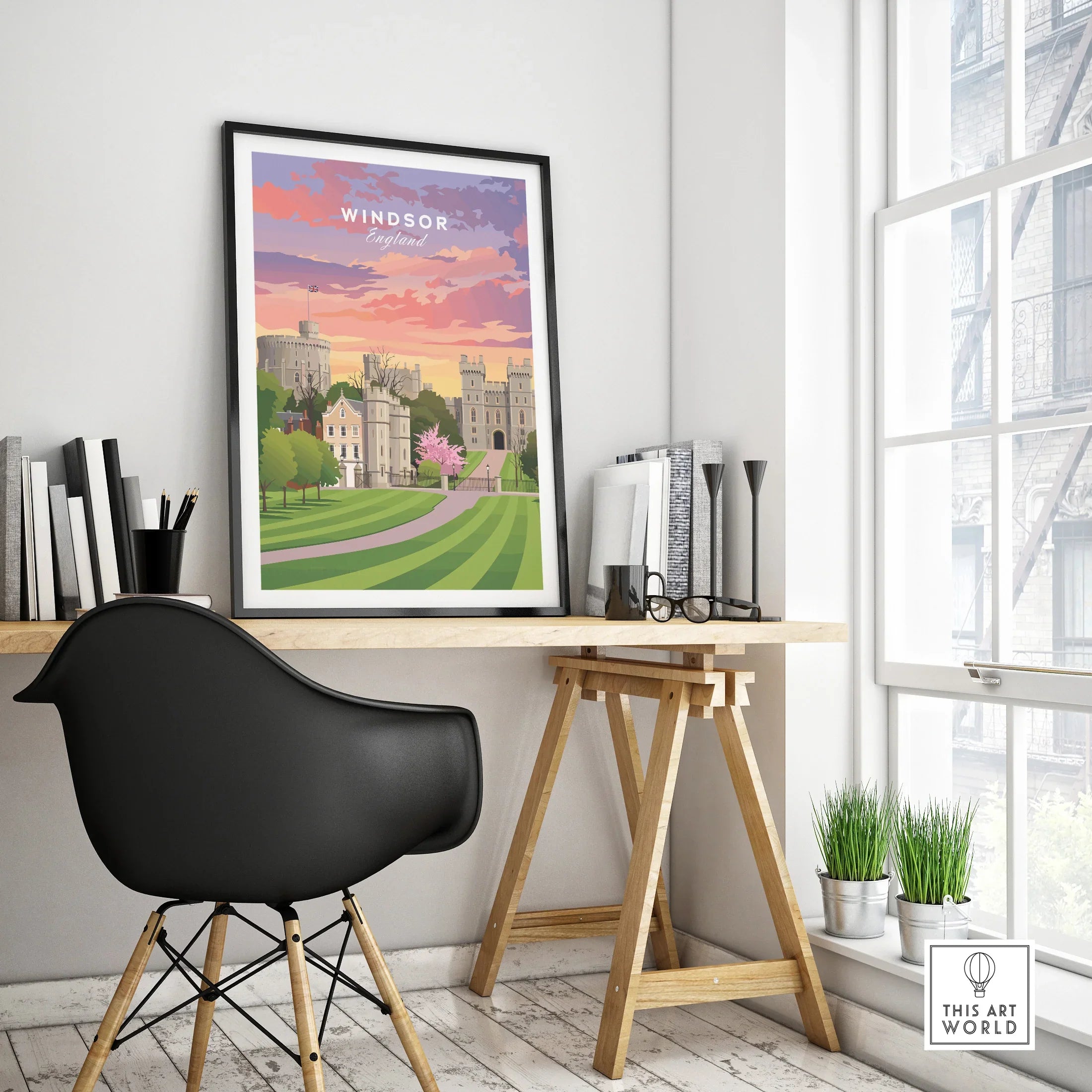 Framed Windsor England travel poster on modern office desk near window, black chair in foreground.