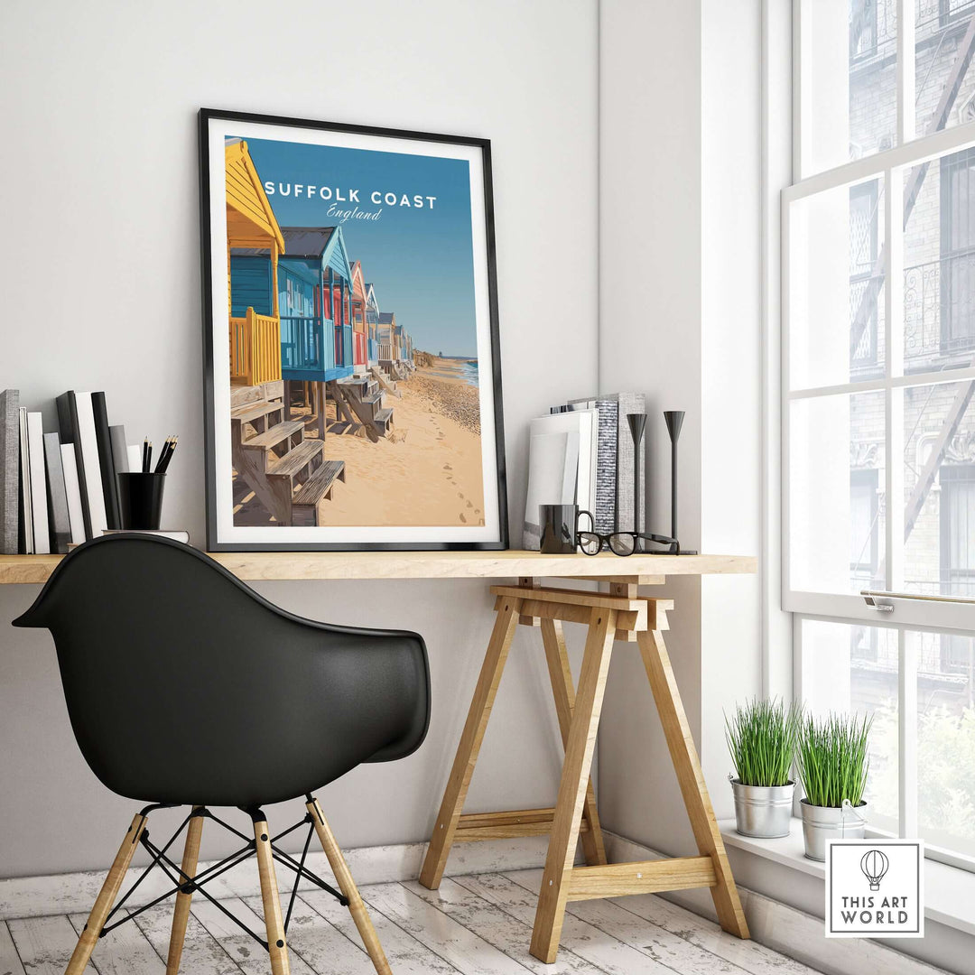 Suffolk Coast England beach huts poster displayed in a modern office setting with a black chair.