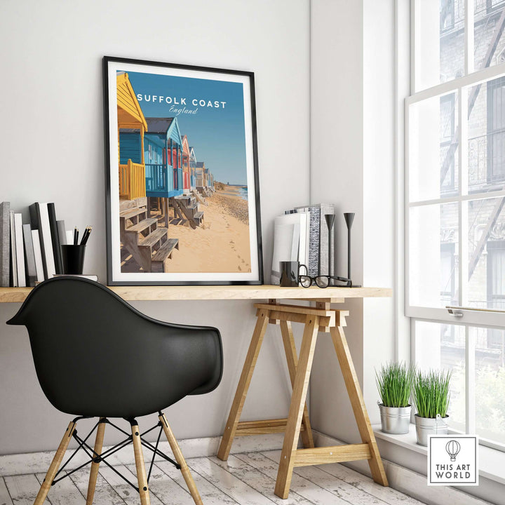 Suffolk Coast England beach huts poster displayed in a modern office setting with a black chair.