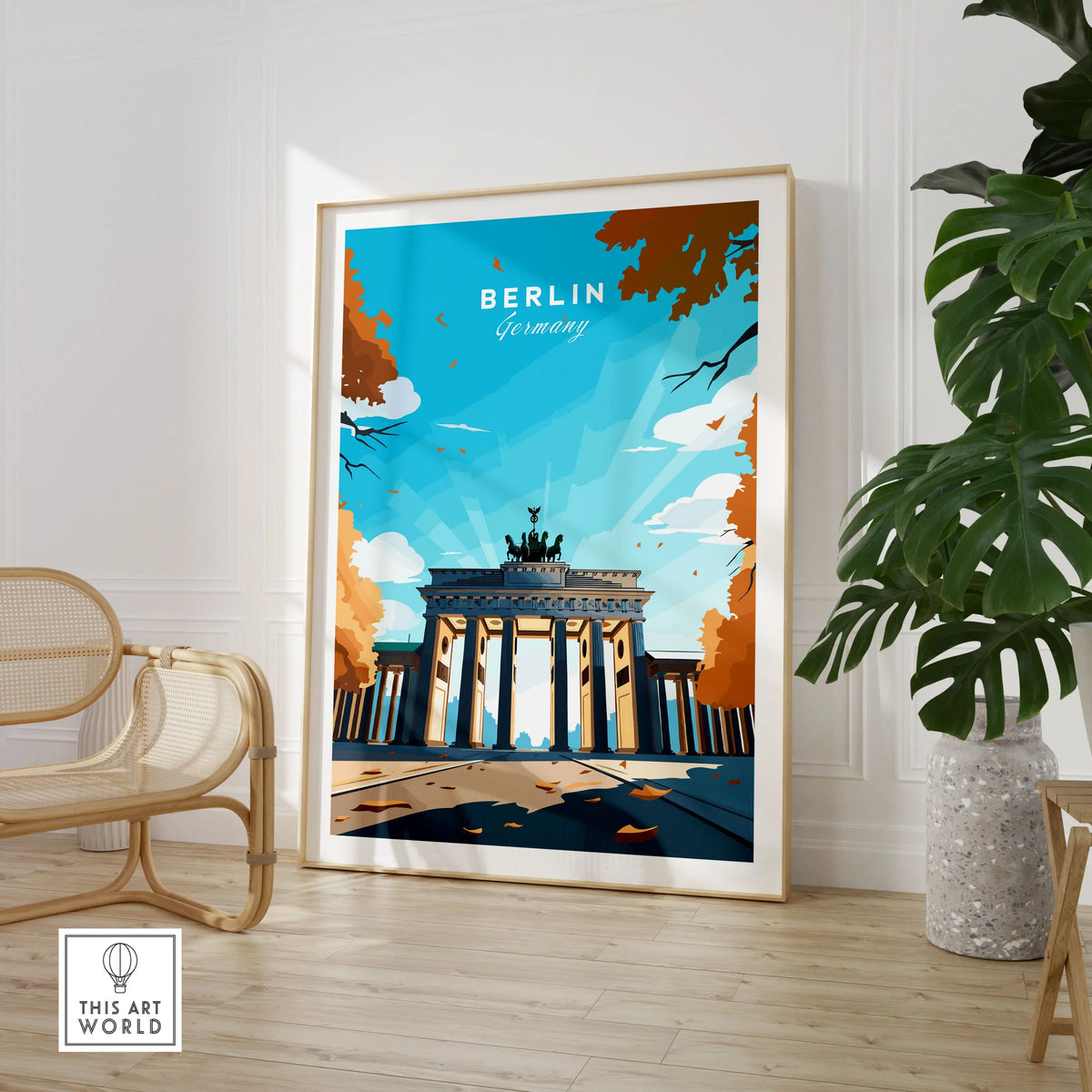 Berlin Poster Blue Sky in a large natural wood frame leaning in a room with a rattan chair and monstera plant
