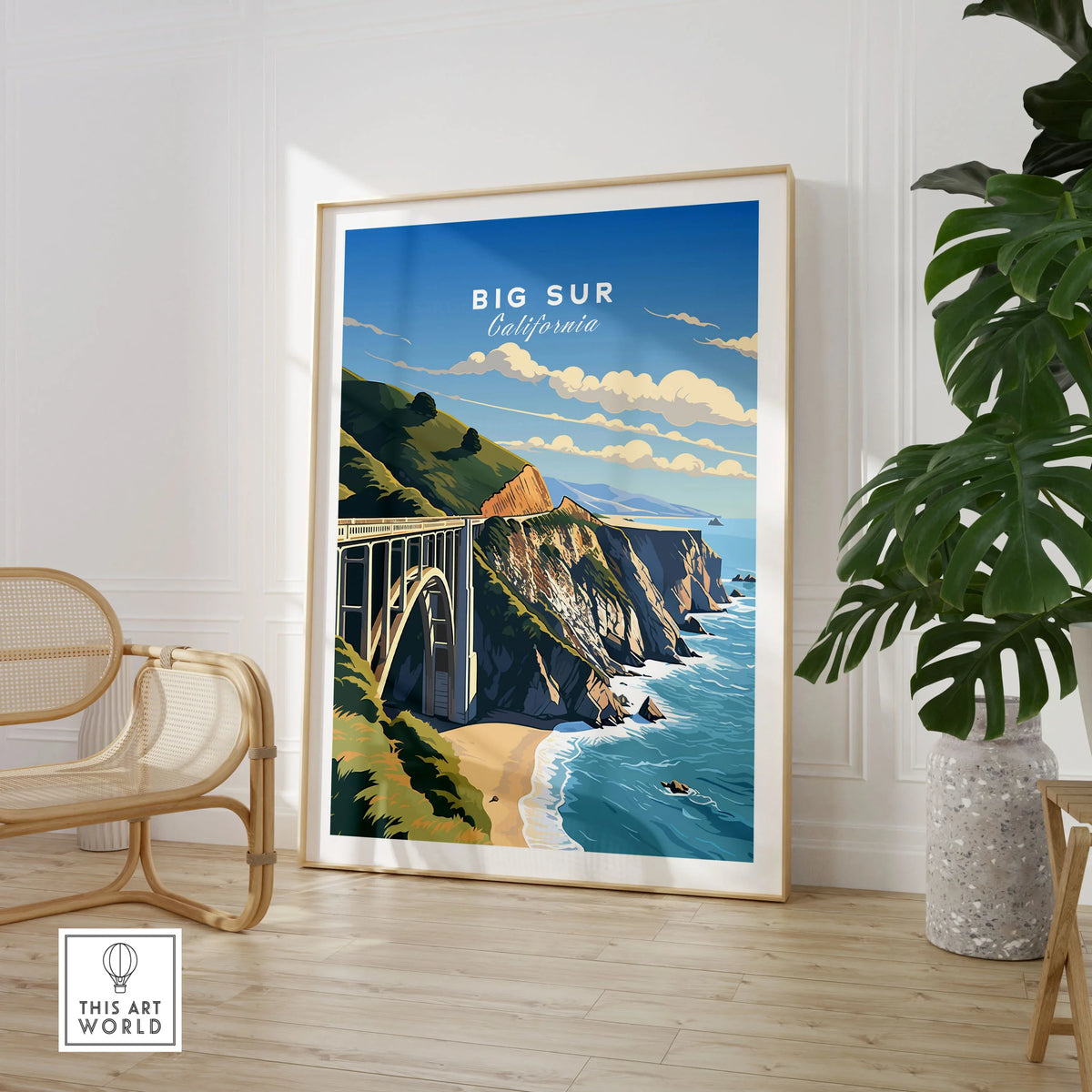 Big Sur Print in a large natural wood frame leaning in a room with a rattan chair and monstera plant