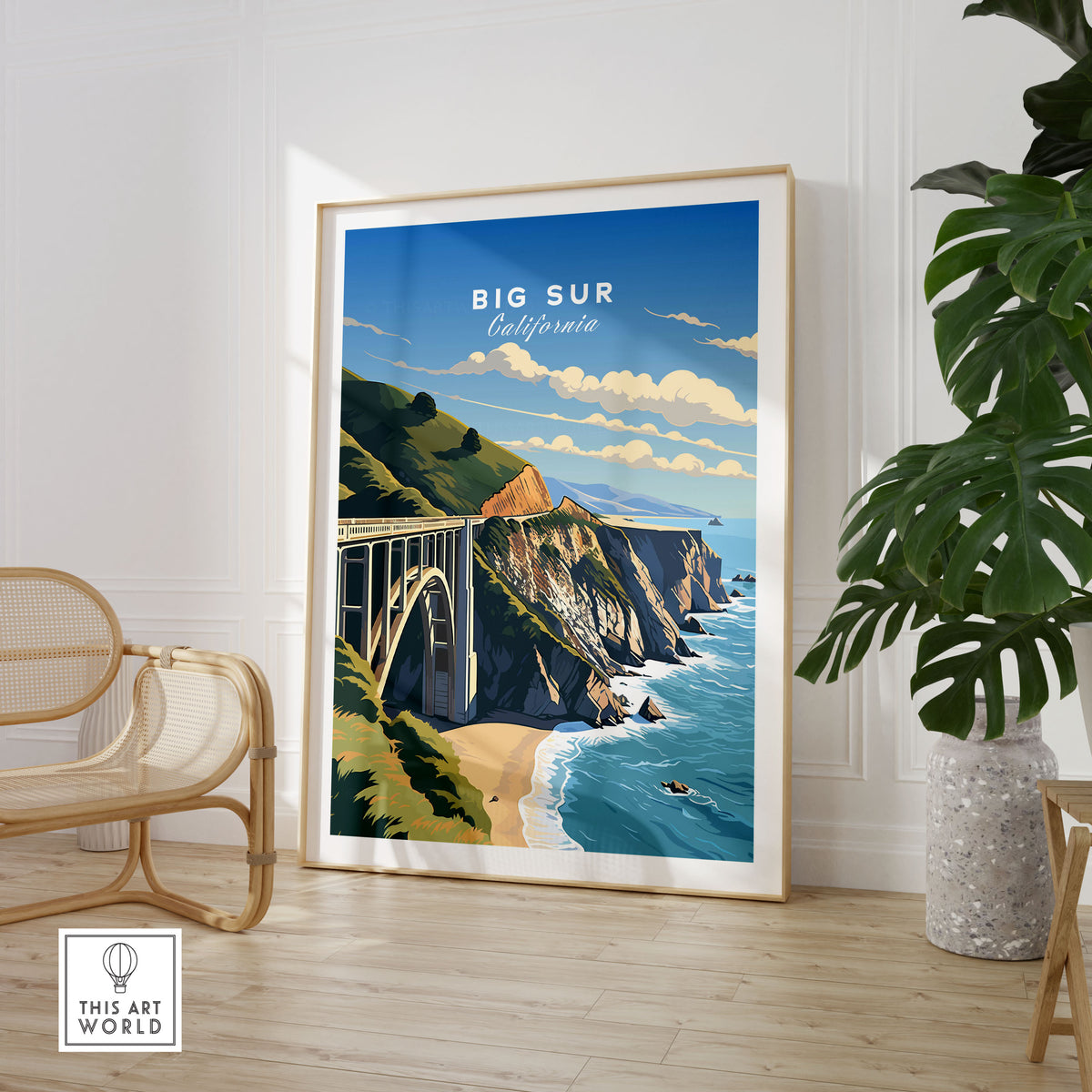 Big Sur Print in a large natural wood frame leaning in a room with a rattan chair and monstera plant