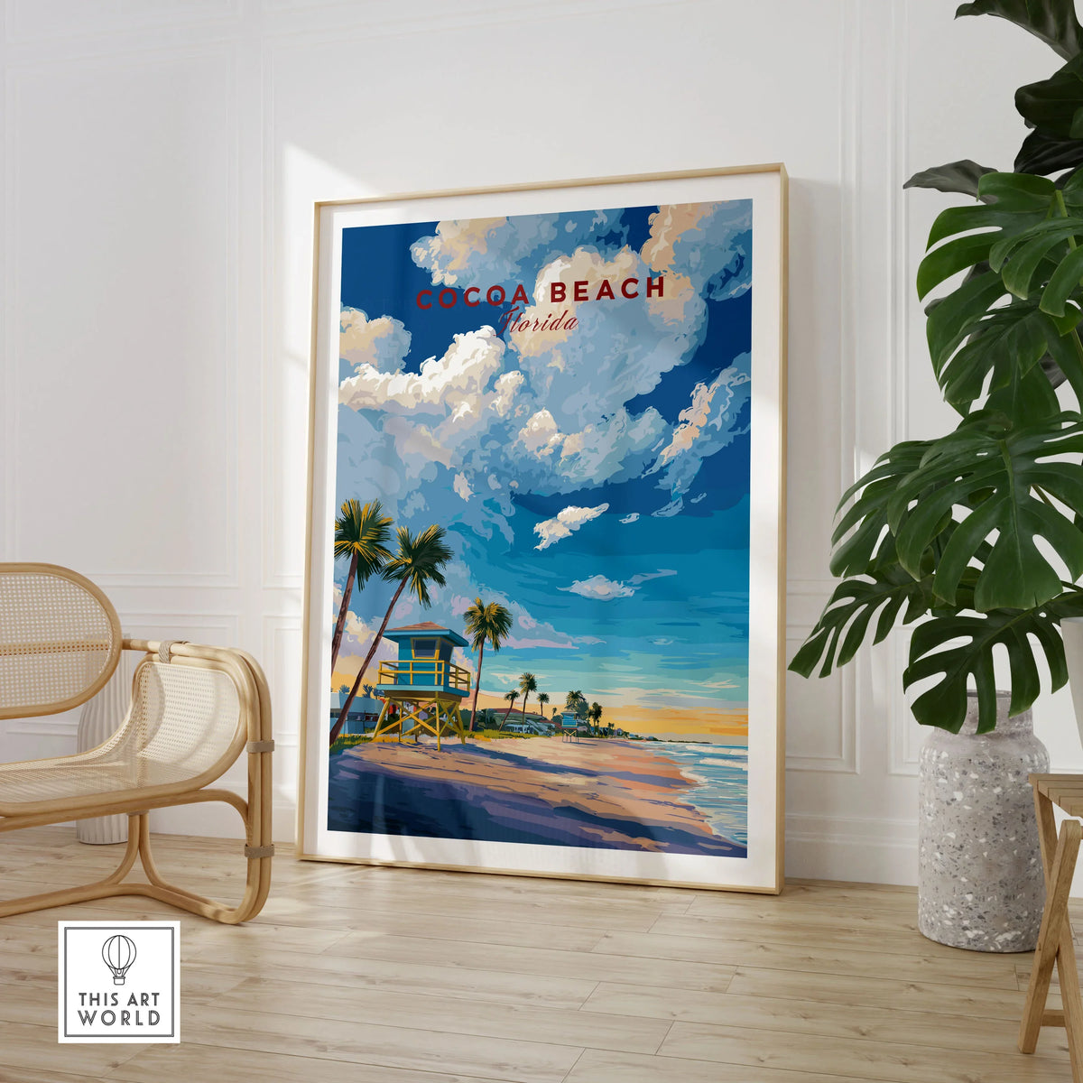 Cocoa Beach Lifeguard Tower Poster - Palm Tree Beach Wall Art in a large natural wood frame leaning in a room with a rattan chair and monstera plant