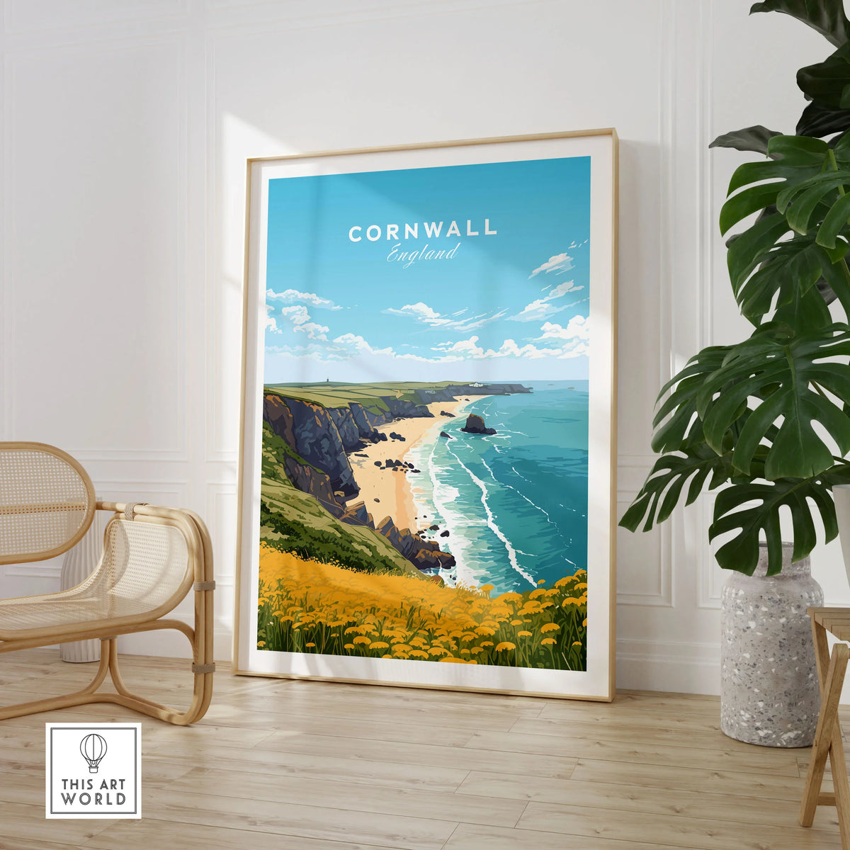 Cornwall Poster in a large natural wood frame leaning in a room with a rattan chair and monstera plant