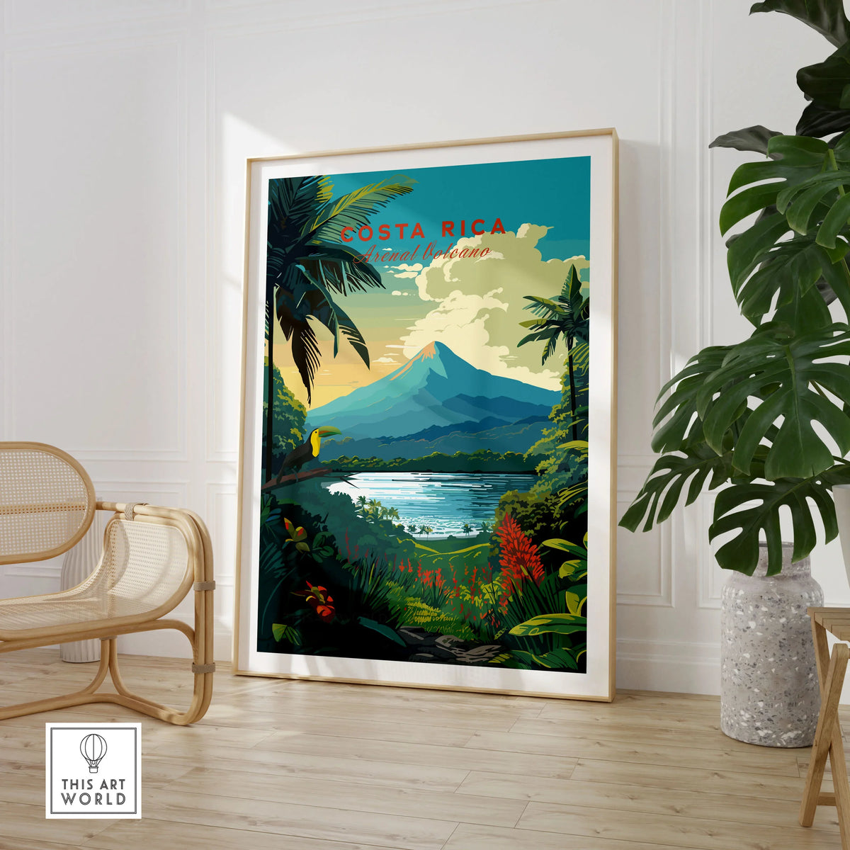 Costa Rica Print in a large natural wood frame leaning in a room with a rattan chair and monstera plant